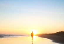 Understanding Consciousness: A Comprehensive Review A lone silhouette of a person running along a serene beach at sunset, reflecting in the wet sand.