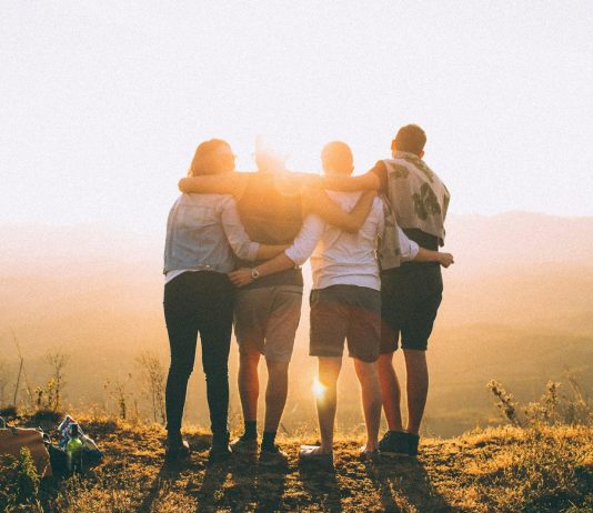 Insights from Owning Your Magnificence ~ Sara Landon four person hands wrap around shoulders while looking at sunset